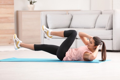 Photo of Young woman in fitness clothes doing exercise at home