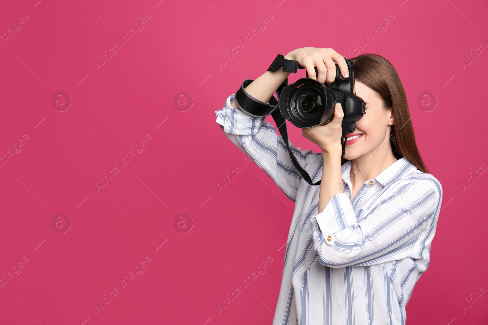 Photo of Professional photographer taking picture on pink background. Space for text