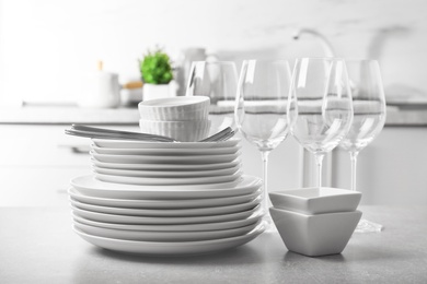 Photo of Set of clean dishes and cutlery on table in kitchen