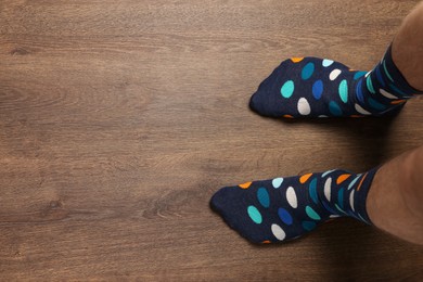 Photo of Man in stylish colorful socks standing on wooden floor, top view. Space for text