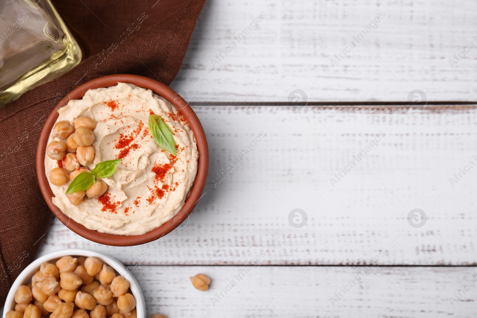 Photo of Delicious hummus with chickpeas and paprika served on white wooden table, flat lay. Space for text