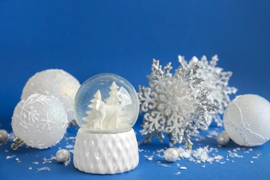 Photo of Beautiful snow globe, Christmas balls and snowflake on blue background