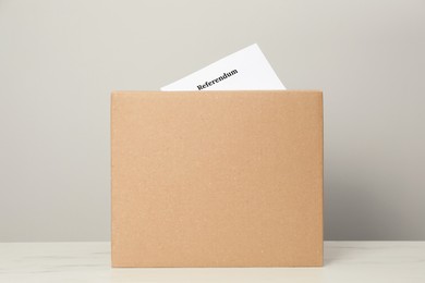 Photo of Referendum ballot in box on table against light grey background