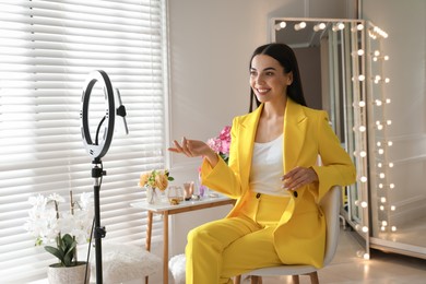 Photo of Blogger recording video in dressing room at home. Using ring lamp and smartphone