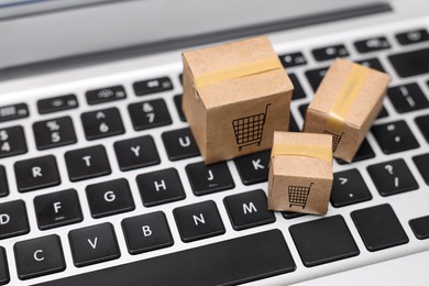 Image of Internet store. Small cardboard boxes with shopping carts on laptop, closeup