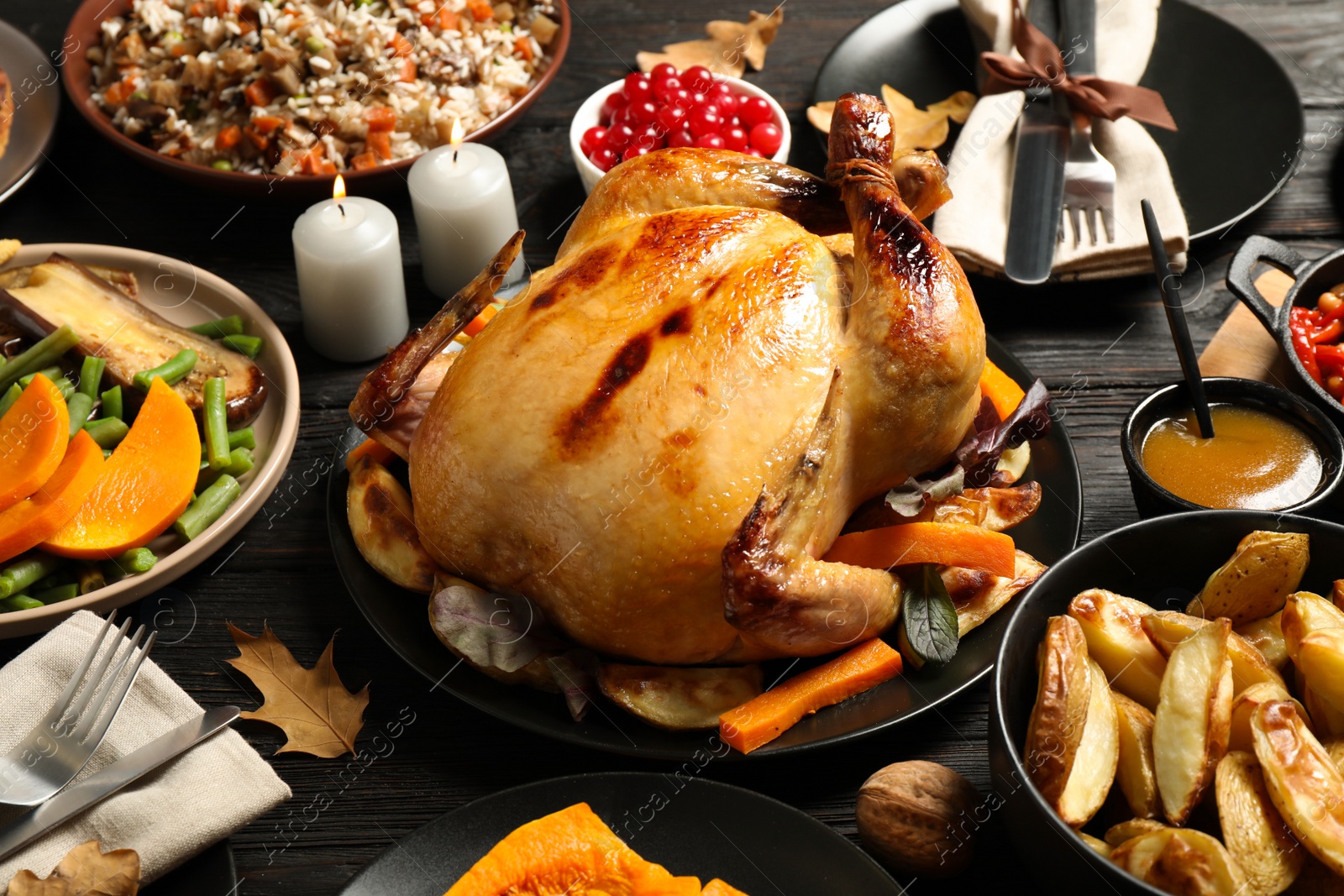 Photo of Traditional Thanksgiving day feast with delicious cooked turkey and other seasonal dishes served on black wooden table