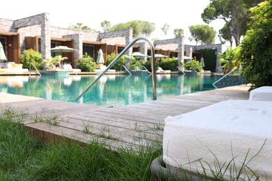 Photo of Outdoor swimming pool with wooden deck and sun loungers. Luxury resort