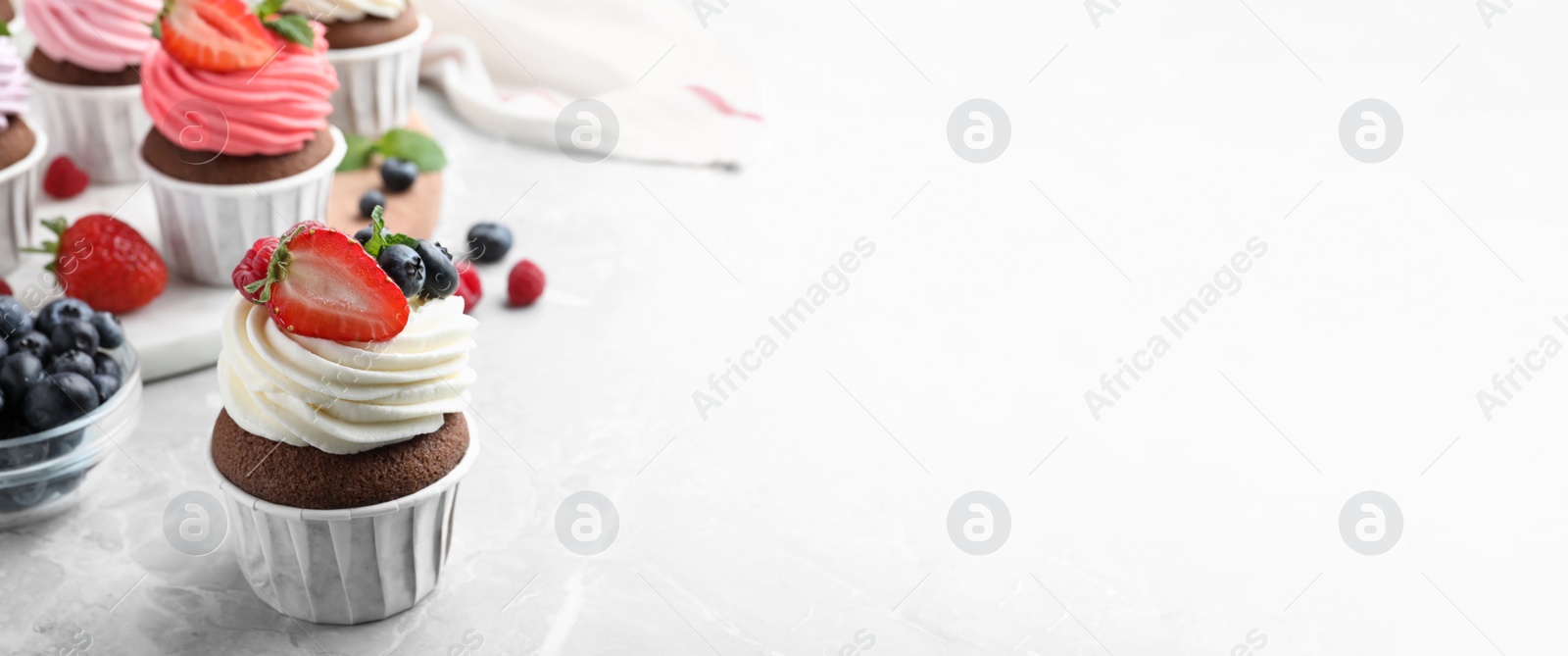 Image of Sweet cupcake with fresh berries on white table, space for text. Banner design