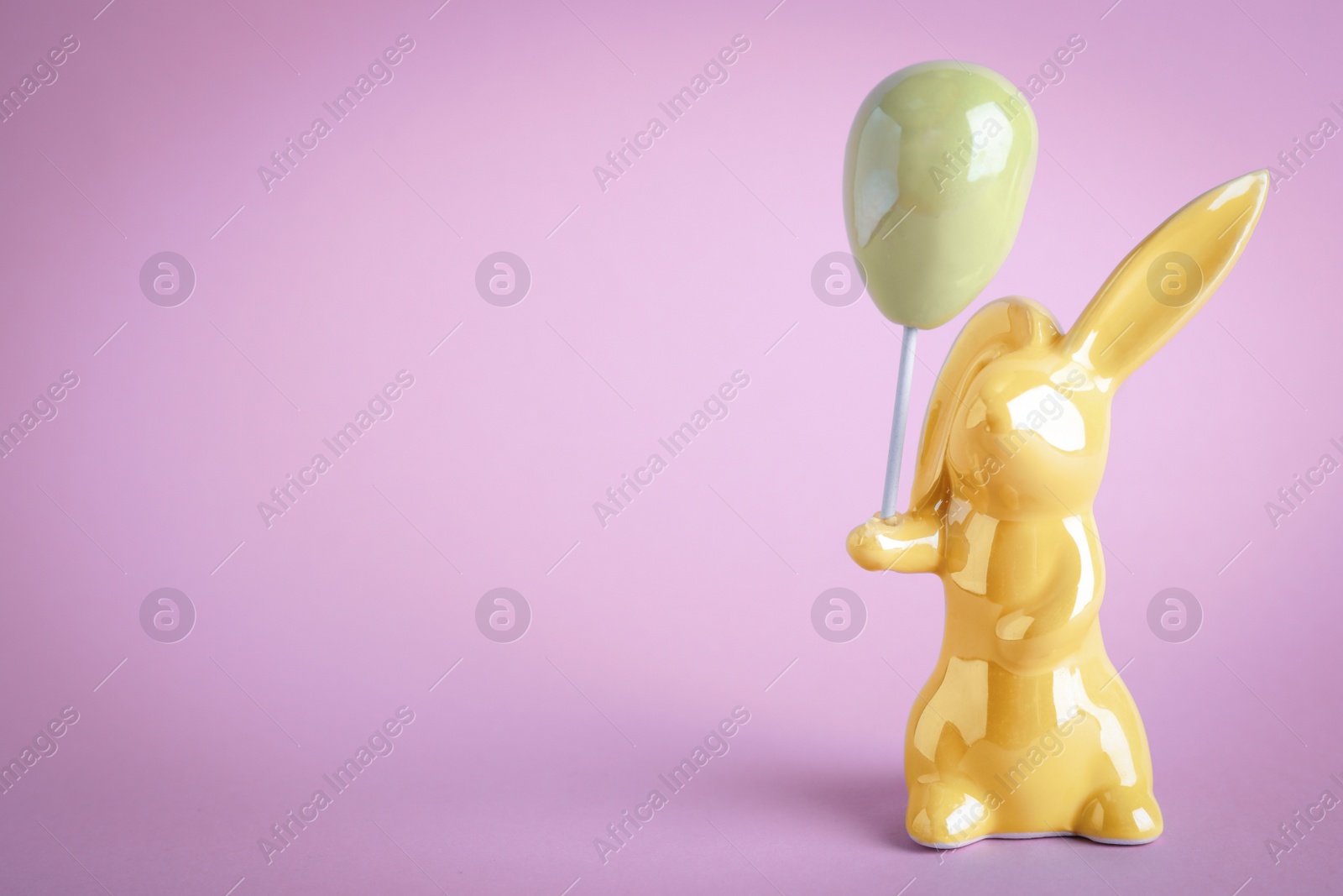 Photo of Easter bunny figure on violet background. Space for text