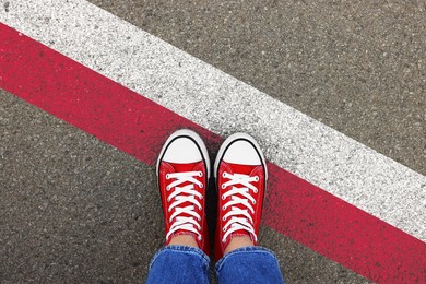 Image of Immigration. Woman standing on asphalt near flag of Poland, top view