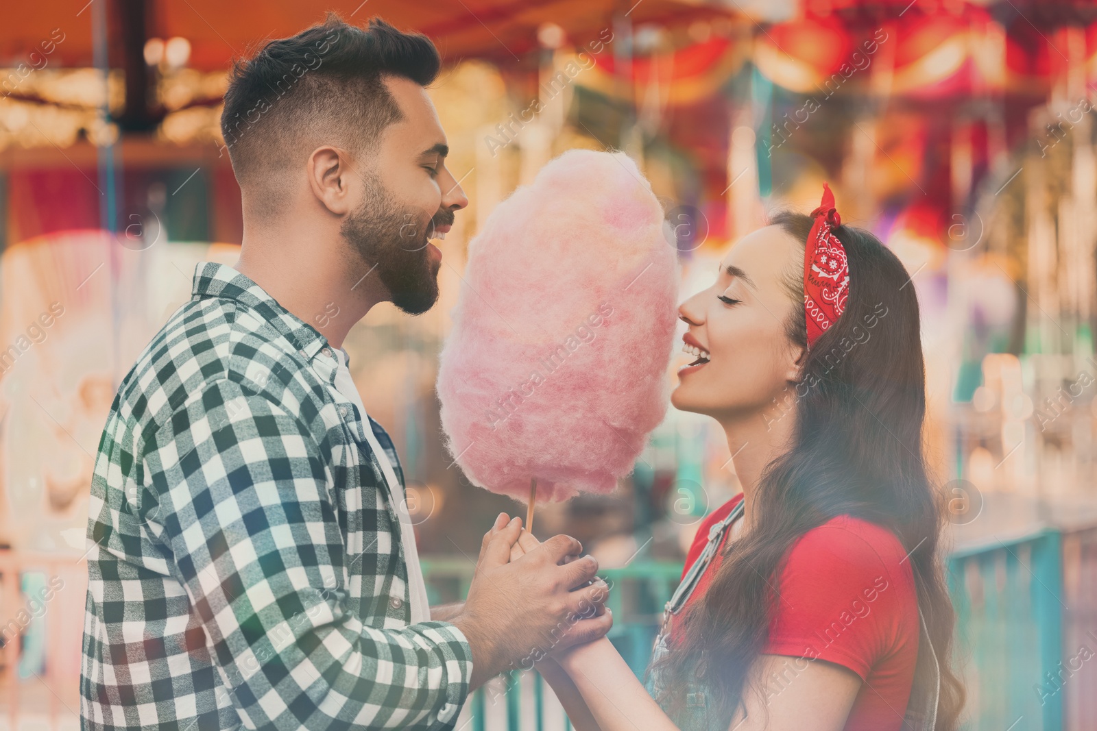 Image of Happy couple eating cotton candy at funfair