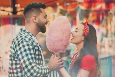 Happy couple eating cotton candy at funfair