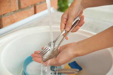 Photo of Woman washing dishes in kitchen sink, closeup view. Cleaning chores
