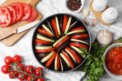 Dressing for delicious ratatouille and different vegetables on white marble table, flat lay