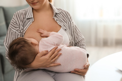 Photo of Young woman breastfeeding her baby at home