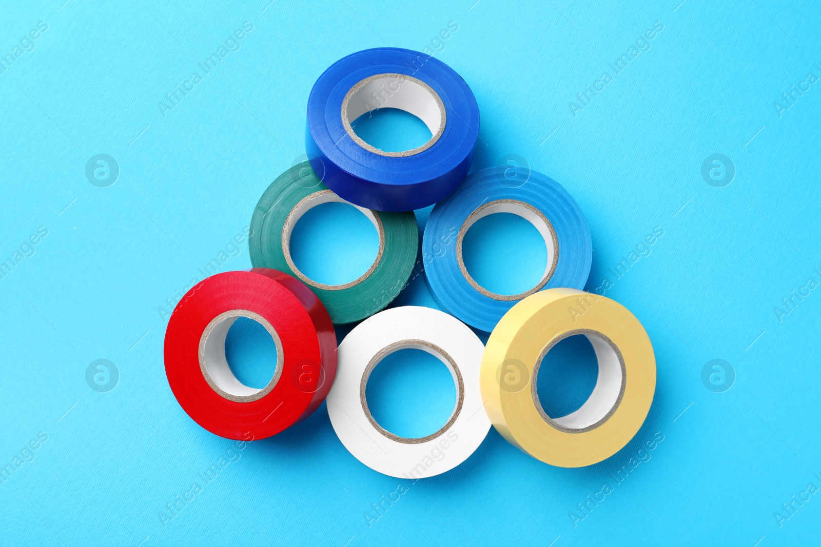 Photo of Colorful insulating tapes on light blue background, flat lay