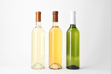 Photo of Bottles of expensive white wines on light background