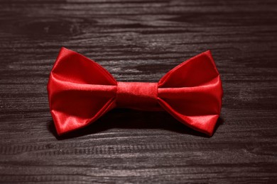Photo of Stylish red bow tie on wooden table, closeup