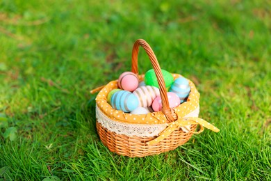 Photo of Easter celebration. Painted eggs in wicker basket on green grass