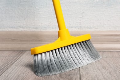 Photo of Sweeping wooden floor with plastic broom, closeup