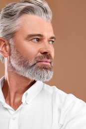 Photo of Portrait of confident man with beautiful hairstyle on light brown background
