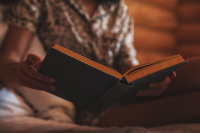 Photo of Woman reading book on bed at home, closeup