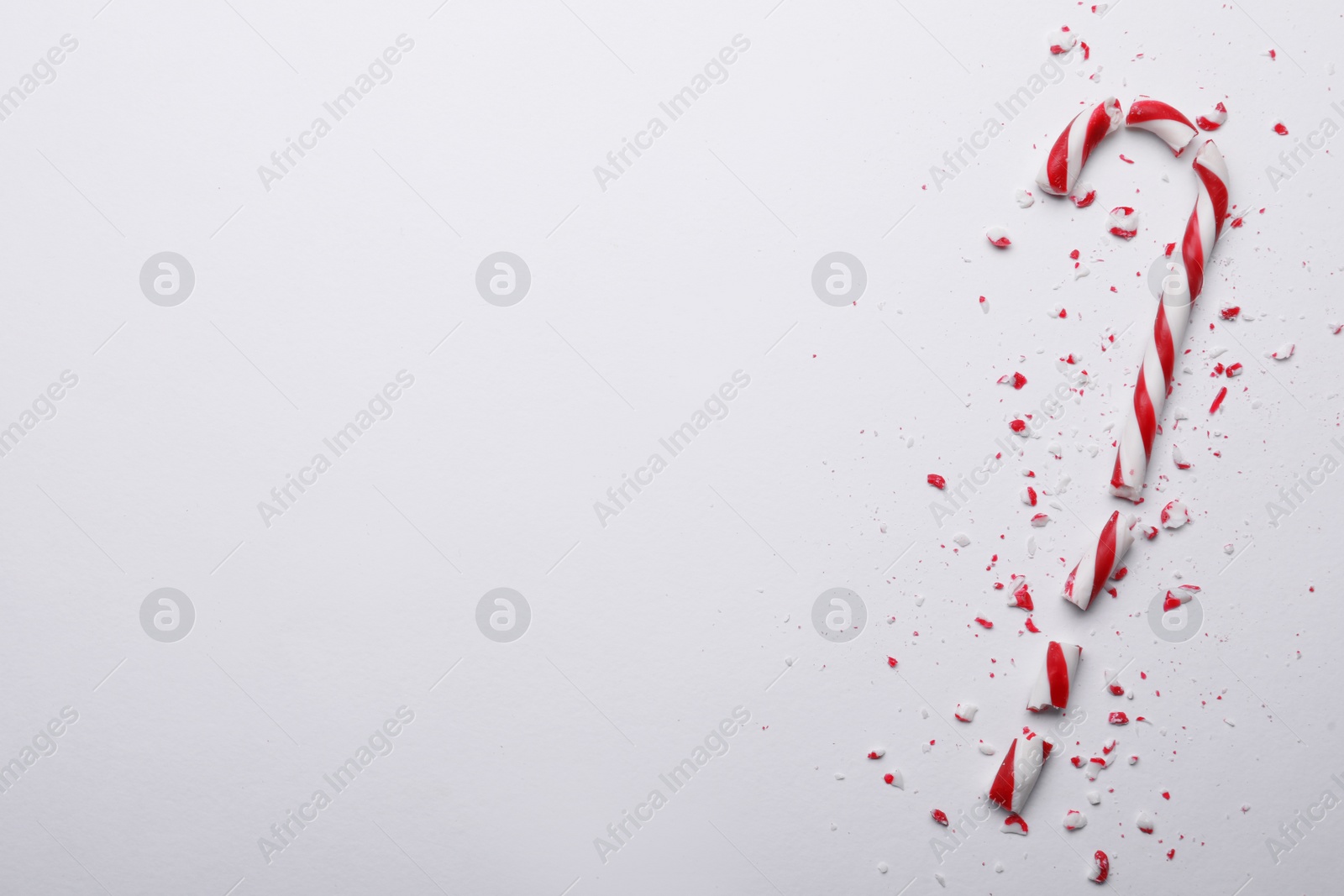 Photo of Broken sweet Christmas candy cane on white background, top view. Space for text