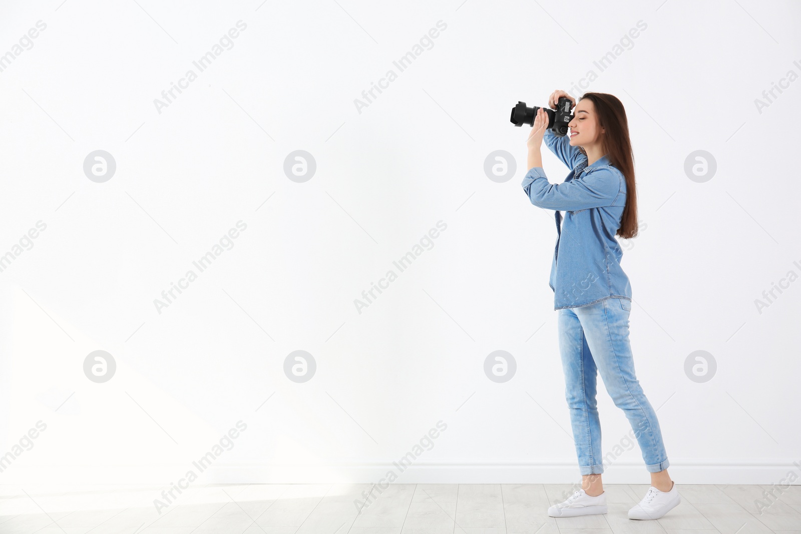 Photo of Female photographer with camera near light wall indoors