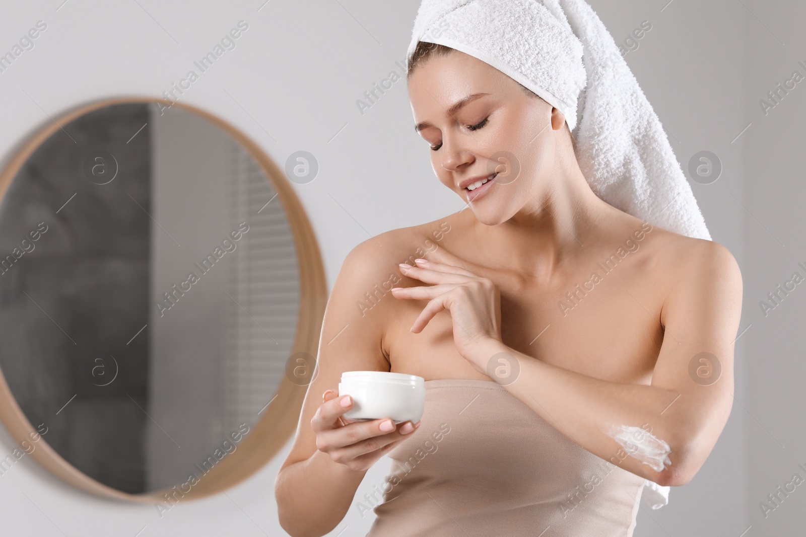 Photo of Beautiful woman with jar of body cream in bathroom, space for text