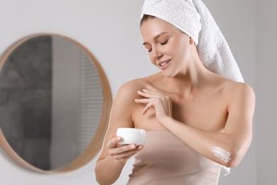 Beautiful woman with jar of body cream in bathroom, space for text