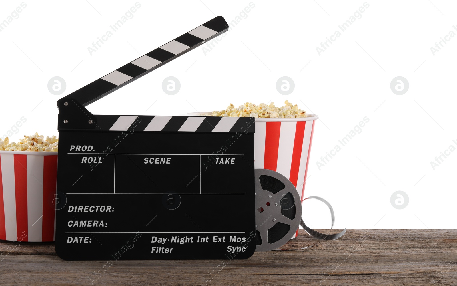 Photo of Movie clapper, buckets of tasty popcorn and film reel on wooden table against white background, space for text