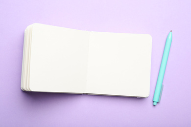 Photo of Stylish open notebook and pen on lilac background, flat lay