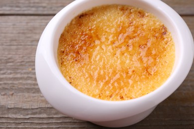 Delicious creme brulee in bowl on wooden table, closeup