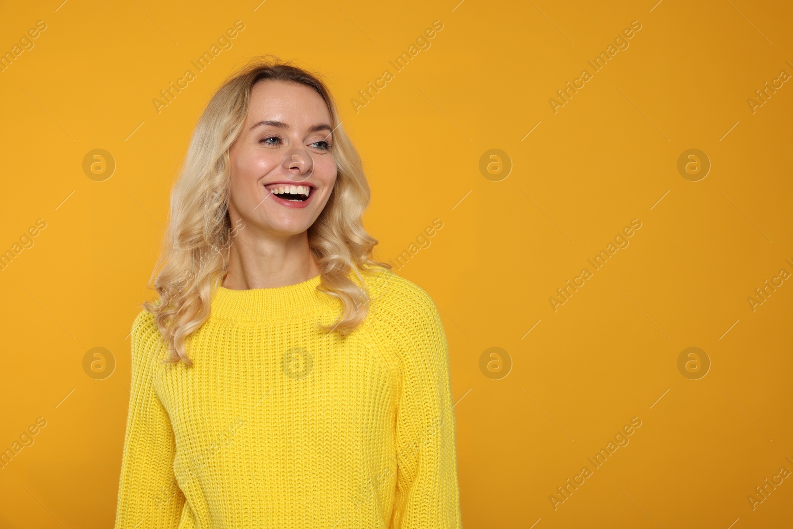 Photo of Happy woman in stylish warm sweater on orange background. Space for text