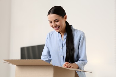 Photo of Happy young woman unpacking parcel at home. Internet shopping