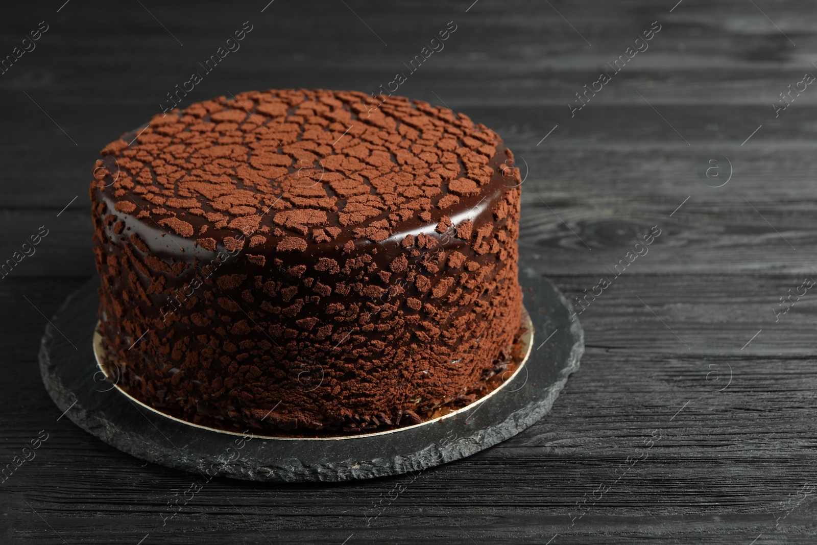 Photo of Delicious chocolate truffle cake on black wooden table, space for text