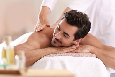 Photo of Handsome young man receiving back massage in spa salon