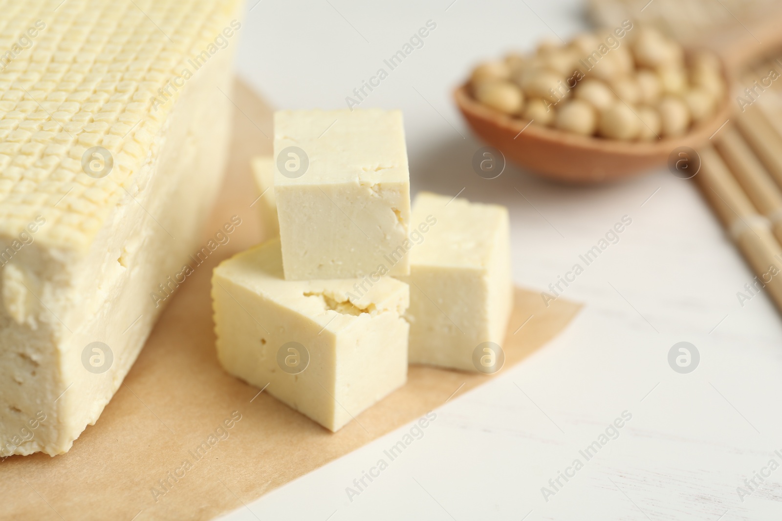 Photo of Cut tofu and soya beans on white wooden table, closeup