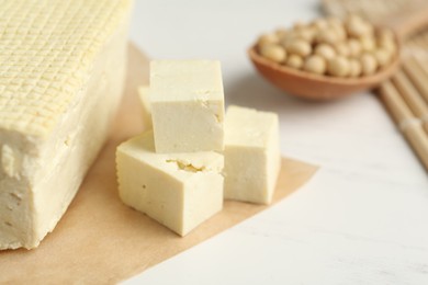 Cut tofu and soya beans on white wooden table, closeup