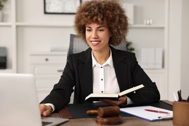 Notary with notebook using laptop at workplace in office