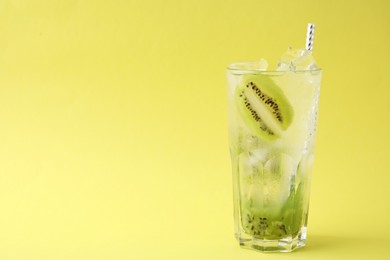 Photo of Glass of refreshing drink with kiwi on yellow background, space for text