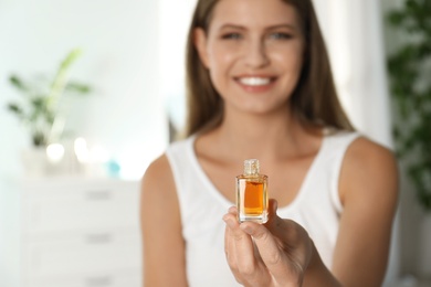 Photo of Young woman holding eyelash oil indoors, closeup