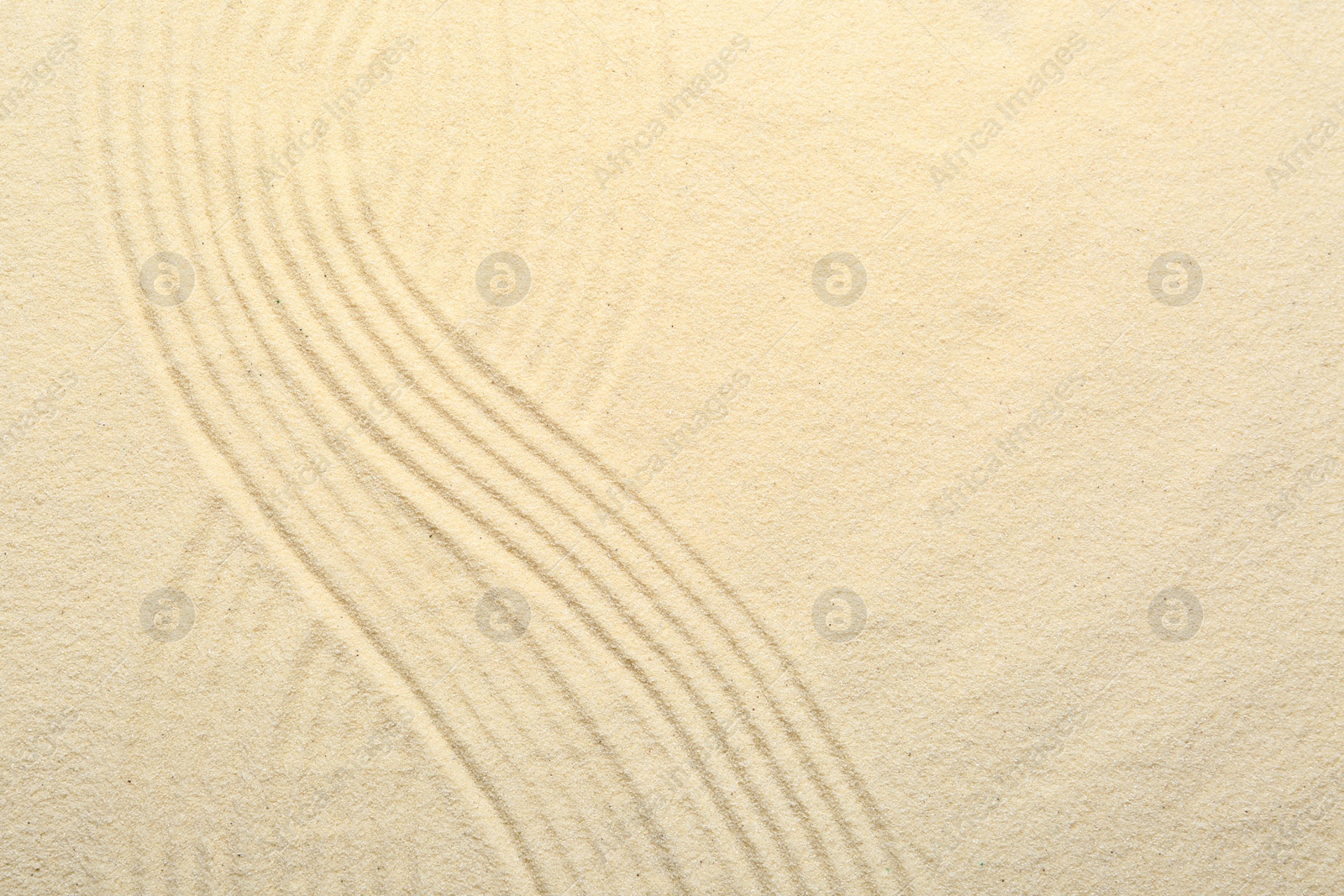 Photo of Zen rock garden. Wave pattern on beige sand, top view