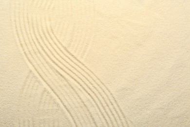 Photo of Zen rock garden. Wave pattern on beige sand, top view