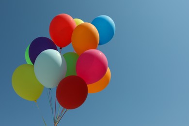 Photo of Bunch of colorful balloons against blue sky. Space for text