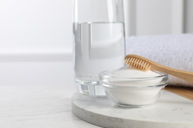 Photo of Bamboo toothbrush, bowl of baking soda and glass of water on white table, space for text