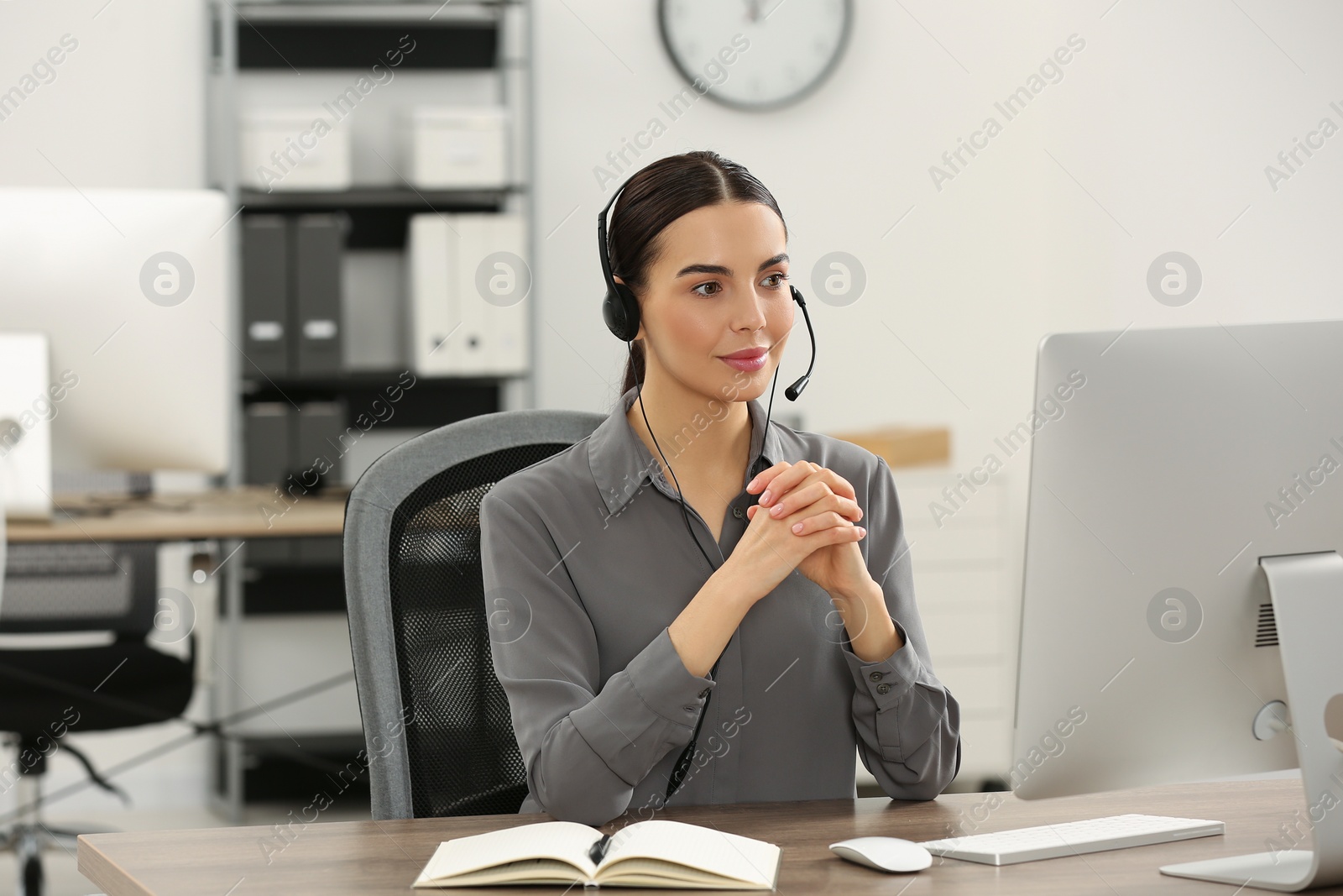 Photo of Hotline operator with headset working on computer in office