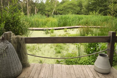 Photo of Beautiful wooden terrace with tin and fishing net near swamp