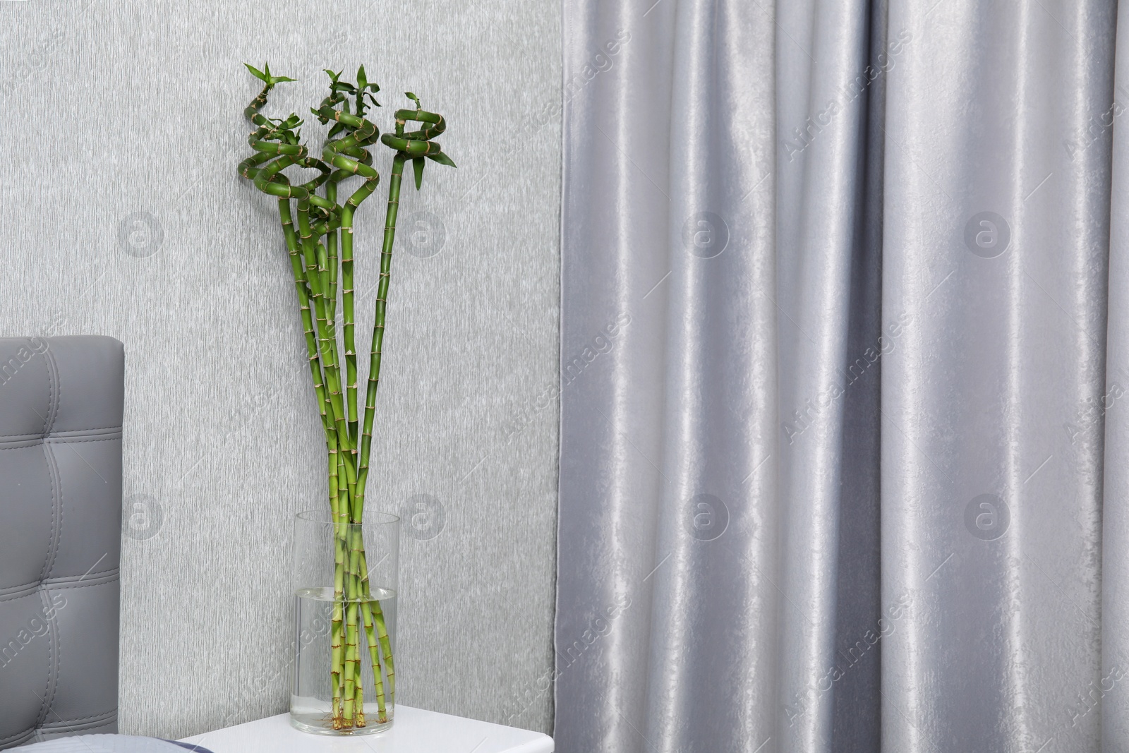 Photo of Vase with beautiful green bamboo stems on white bedside table indoors