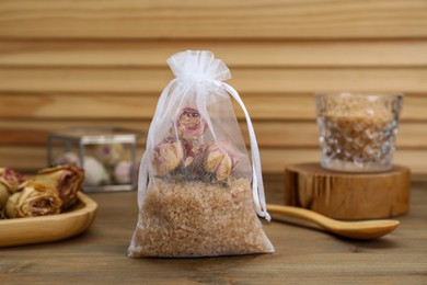 Photo of Scented sachet with dried roses and sea salt on wooden table